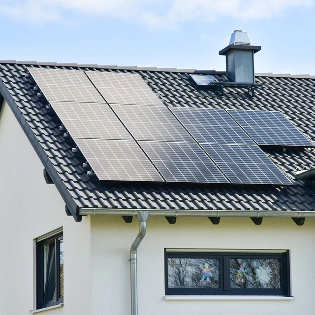 Außenansicht eines privaten Hauses mit einem Fokus auf das Satteldach, das mit Solarmodulen bedeckt ist.